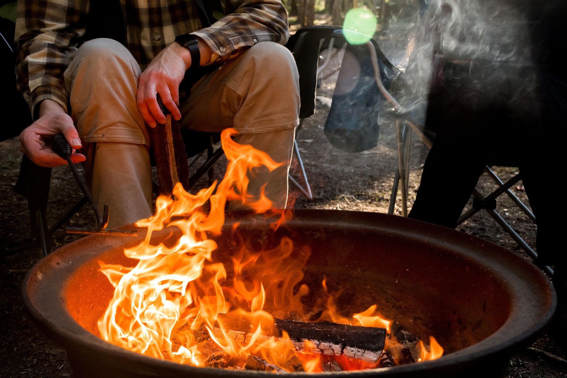 Campfire burning in a firepit . People sitting around. Camping life. Outdoor recreation.